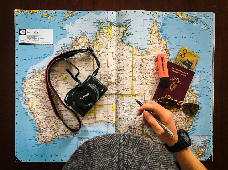 person holding a passport, a camera and a map