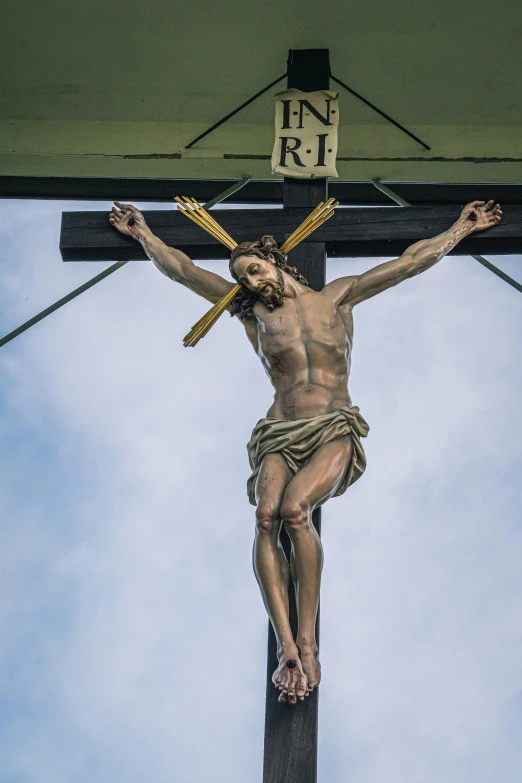 a statue of jesus christ on the cross against a blue sky