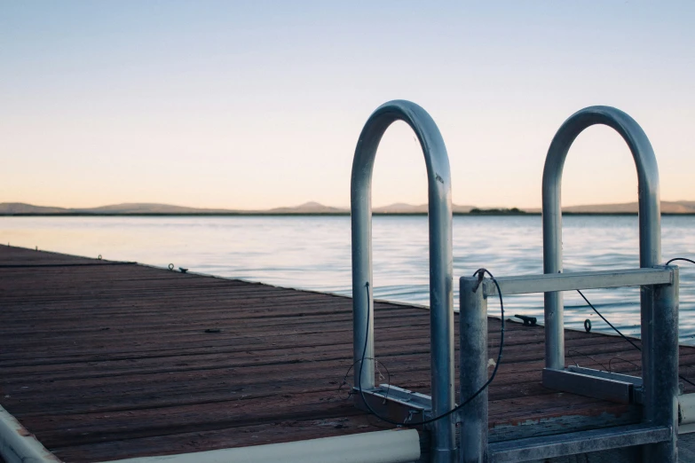 an empty dock in the ocean with the sun rising