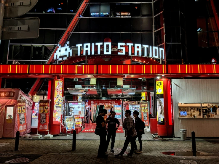 people standing outside a tattoo station in the dark