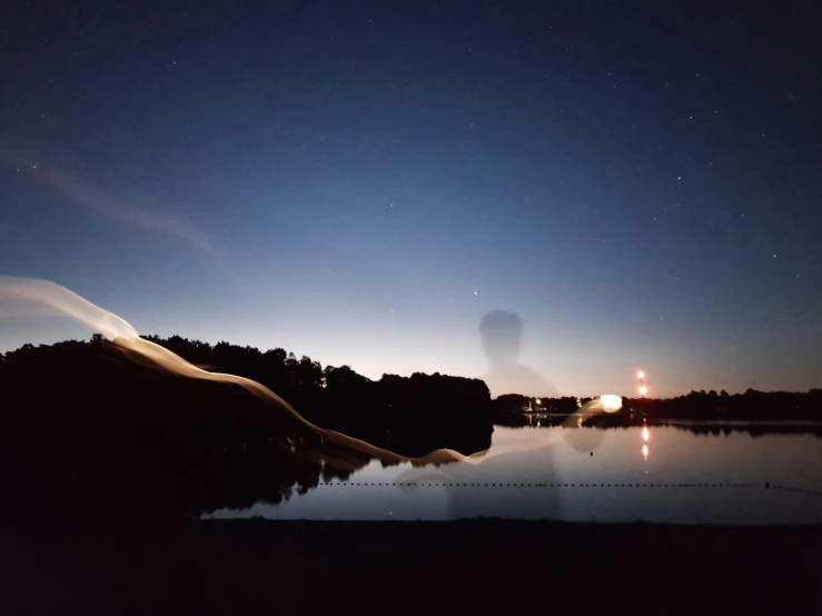 a lake at dusk with trees on the other side