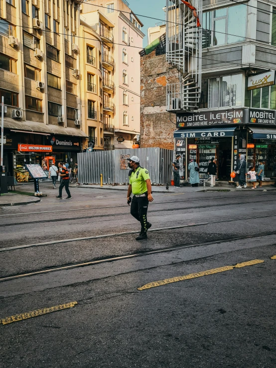 a couple of men walking down a street with a green jacket on