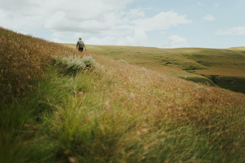 a man in a jacket and backpack walks along the side of a hill