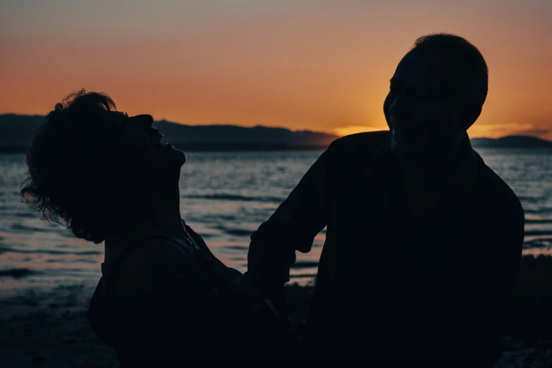 two people standing next to each other on a beach