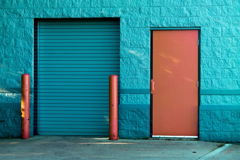 this blue garage door has two orange posts in front