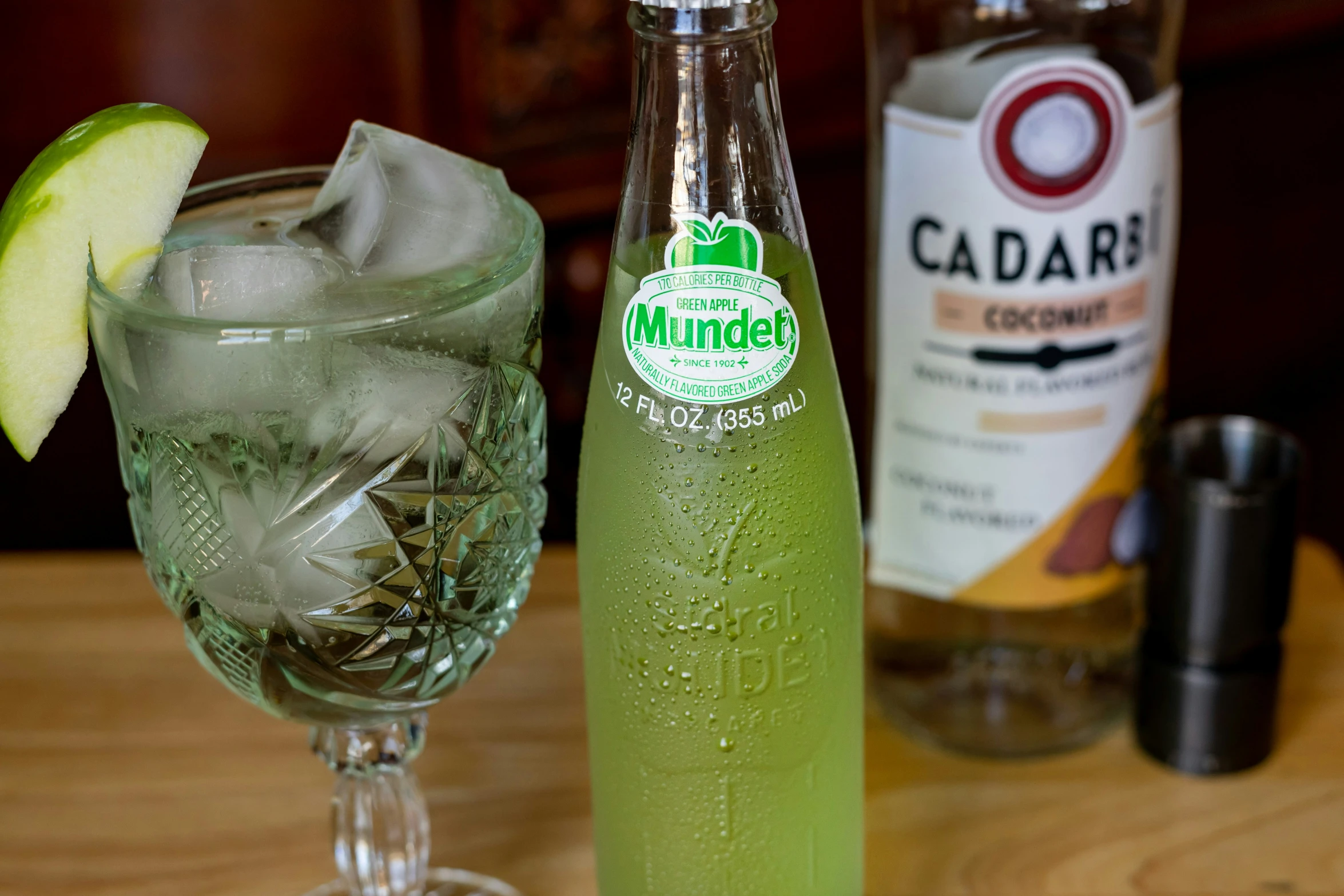 a bottle of munchels next to a glass with ice and lime