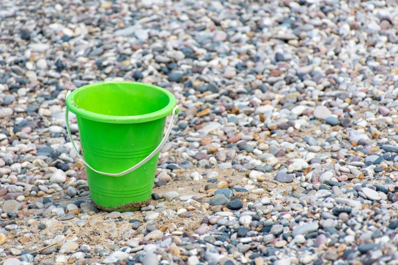 a bucket is sitting in the gravel outside