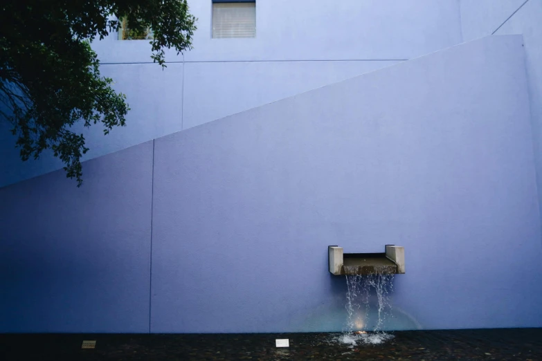 a blue wall with a water spout outside