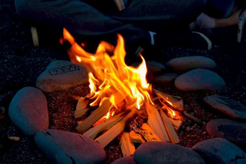 fire being prepared in an open area surrounded by rocks