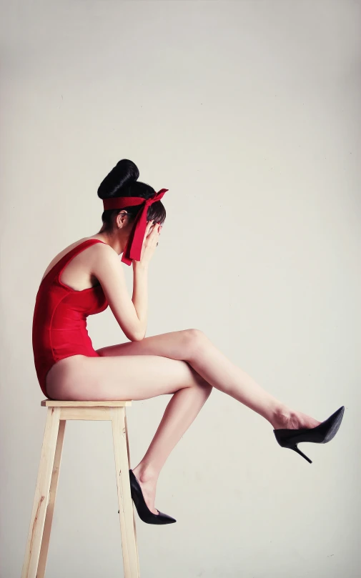 a woman wearing short legs and high heels sitting on a stool