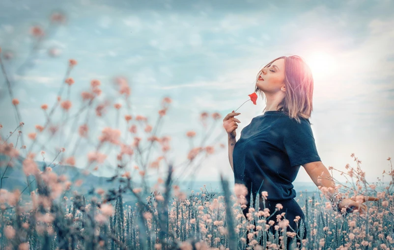 a woman holding a flower up to her mouth