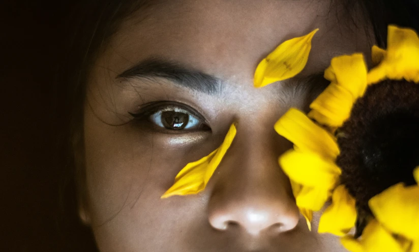 the woman is posing for a pograph with yellow flowers in front of her face