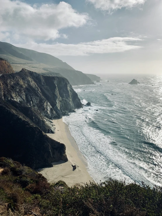 there is a small beach with waves coming in and a man walking