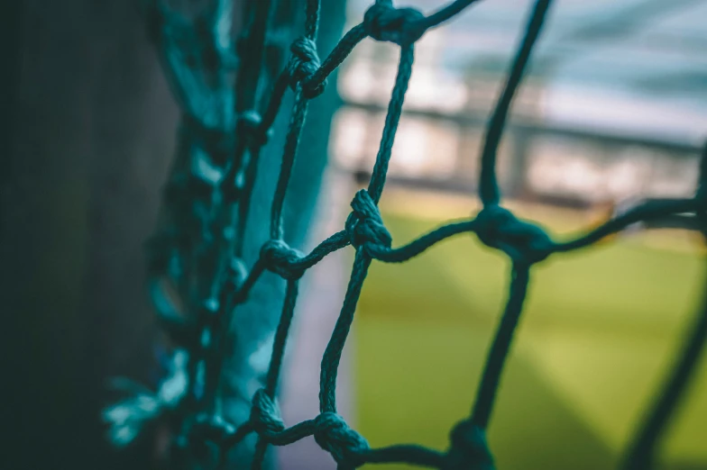 a wire fence with a baseball field in the background