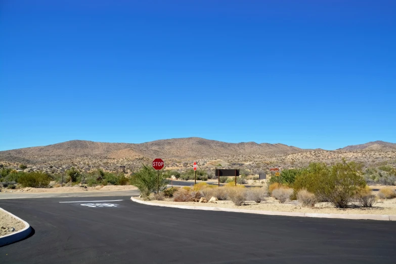 the view of an empty intersection with hills in the background