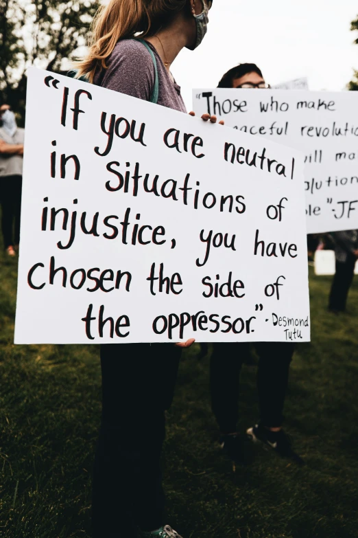 two people holding a sign with words on it