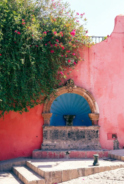 a bench sitting in front of a bright pink building