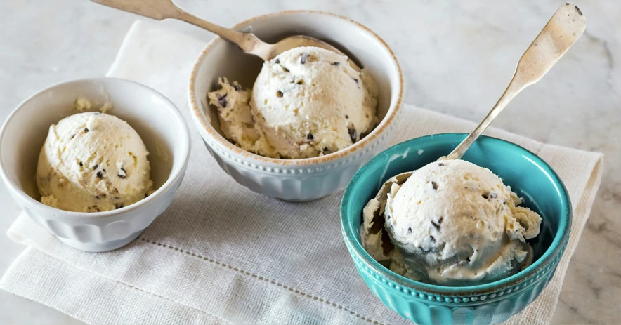 two bowls are holding ice cream and a wooden spoon