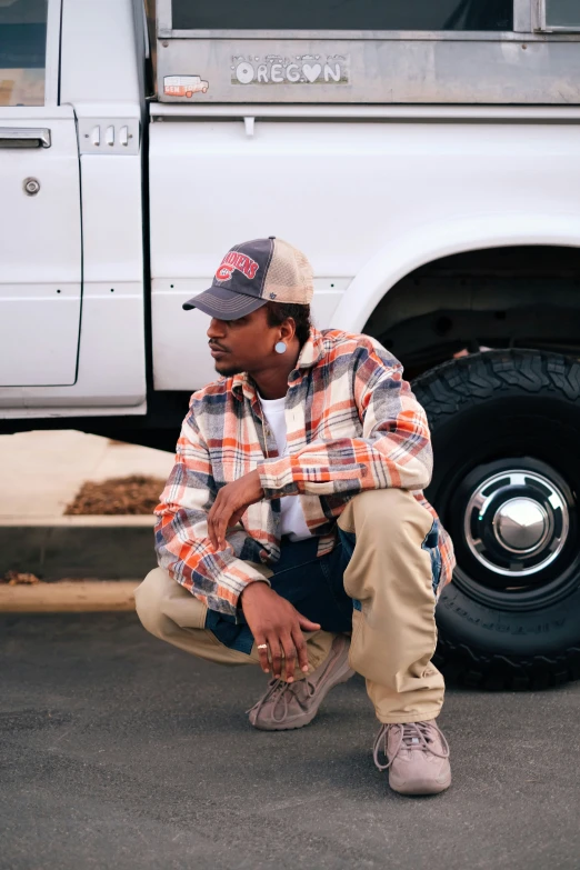 an image of a man squatting near a truck