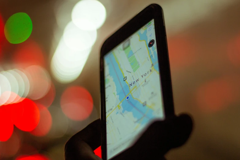 a hand holds up a smartphone while it displays a map