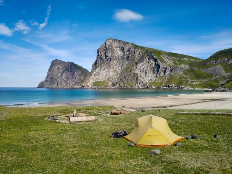 a yellow tent in the green grass near the water