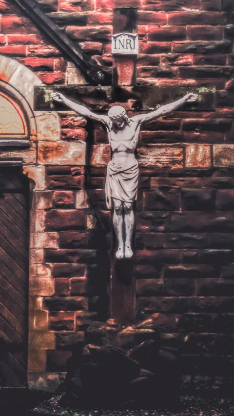 the figure of christ is placed on the side of an old brick building