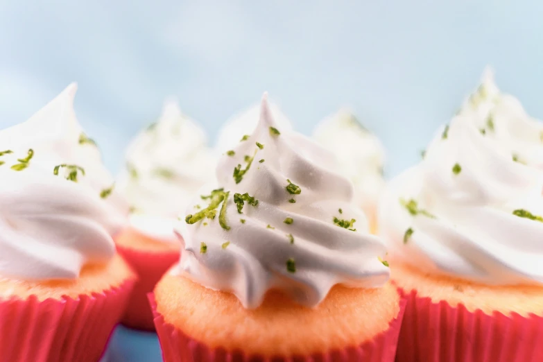 cupcakes with white and green icing on a red plate