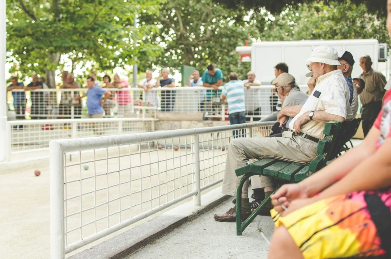 a bunch of people sitting on chairs near a fence