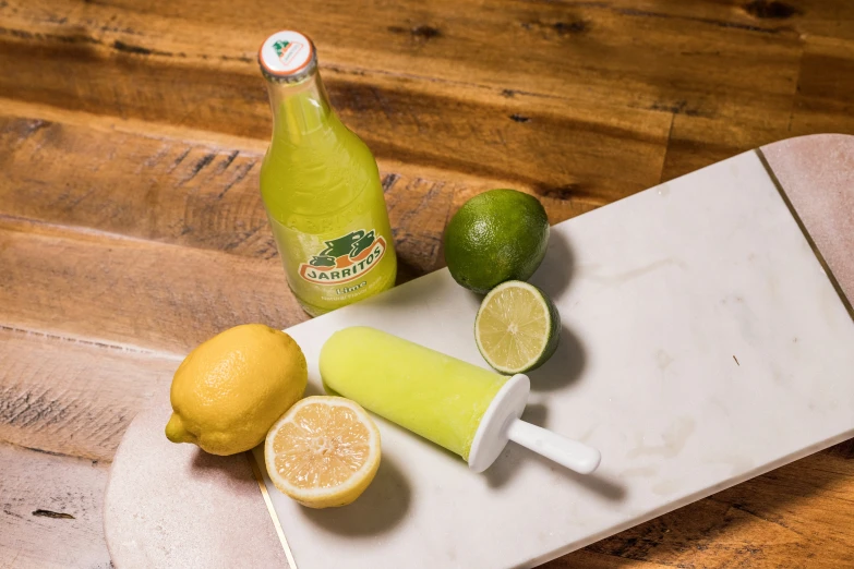 a bottle of green juice next to slices of lemon