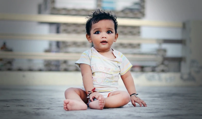 a baby sits on the ground and poses for a picture