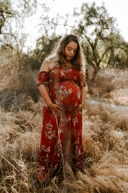 a beautiful pregnant woman standing in an open field