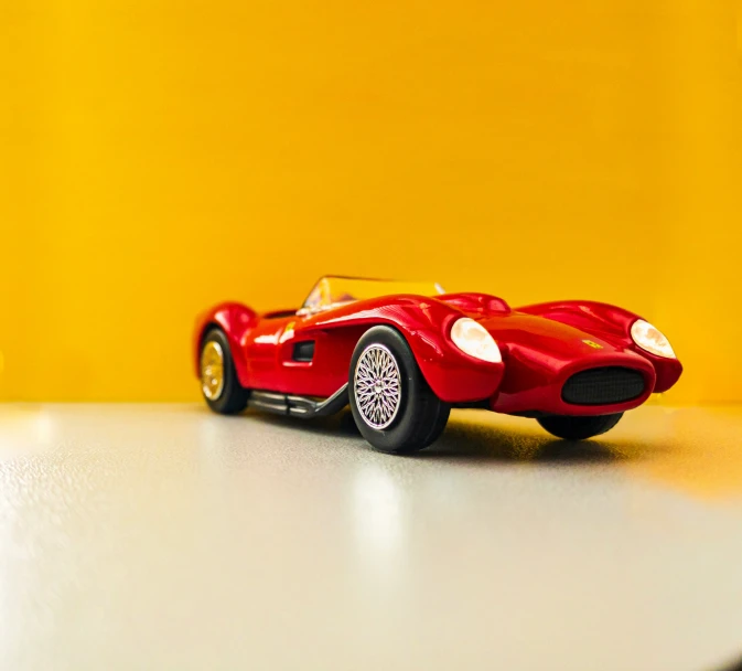 a red model car sitting on a white table