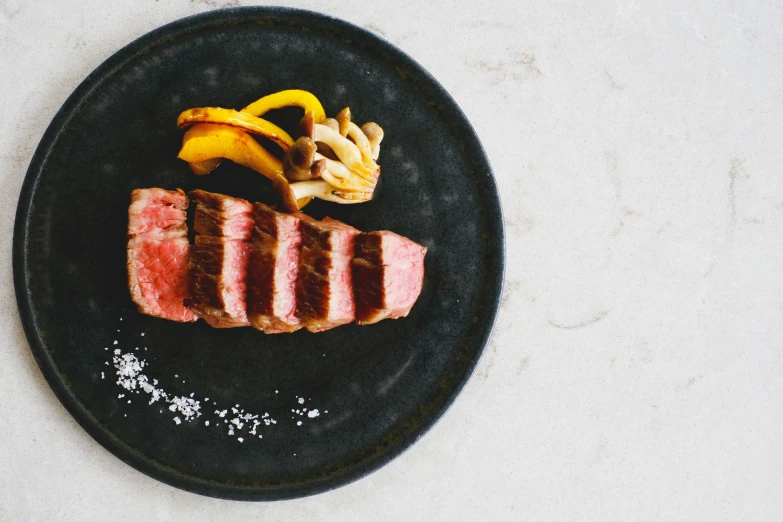 a plate filled with meat next to sliced fruit