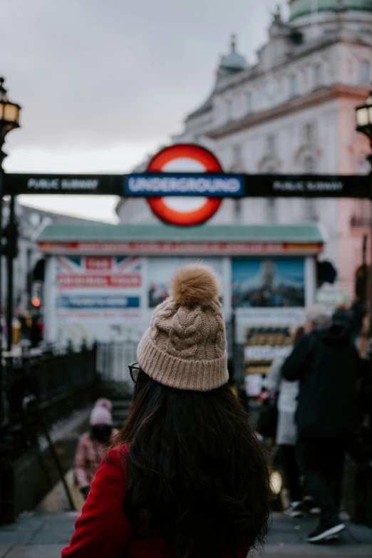 people walking near a tube walk with a big red sign