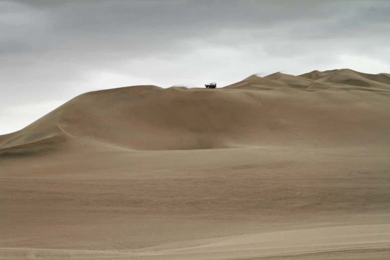 the person on top of the hill is moving along with his motorcycle