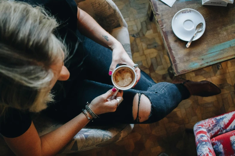 a girl sitting down and drinking from a cup