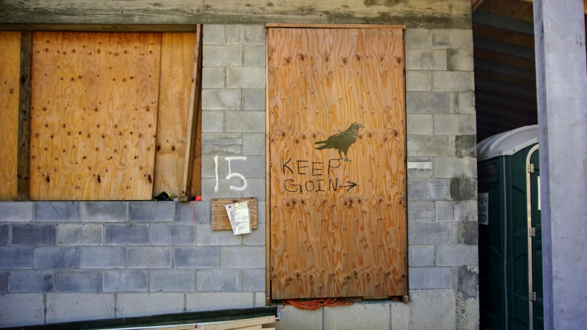 the side of a building with wooden doors and bird on it