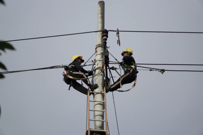 electricians working on a power pole with sky background