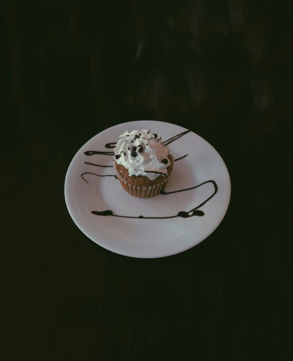 chocolate cupcake with frosting on a white plate