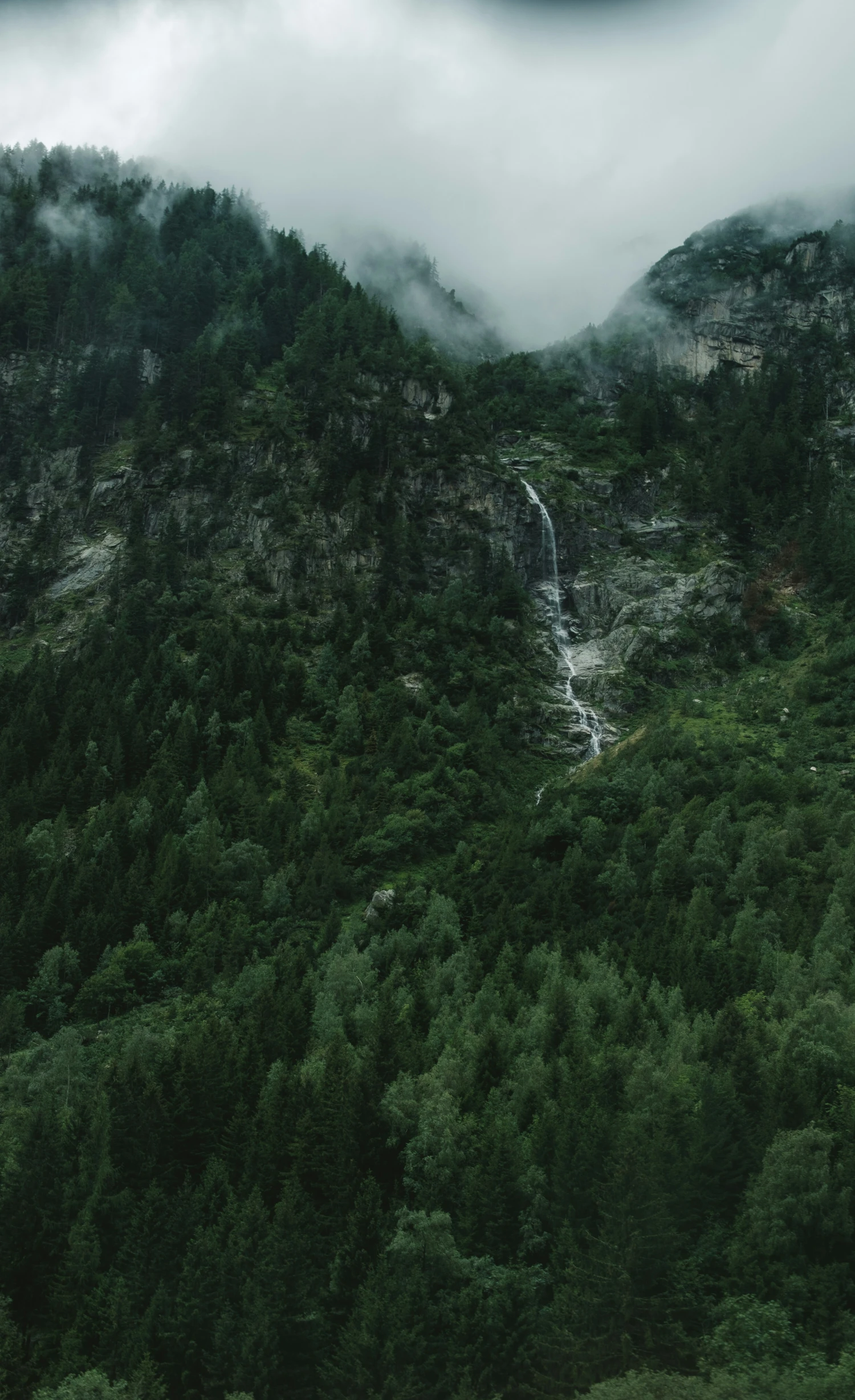 a small waterfall on the side of a large mountain