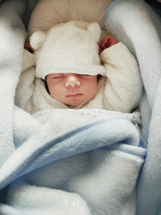 a baby wearing a white teddy bear hat