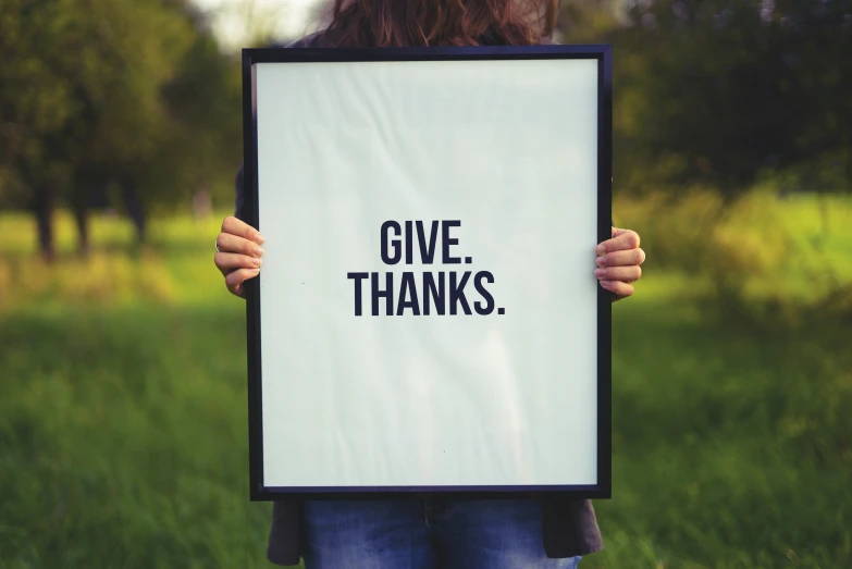 a person holding up a framed sign with words on it