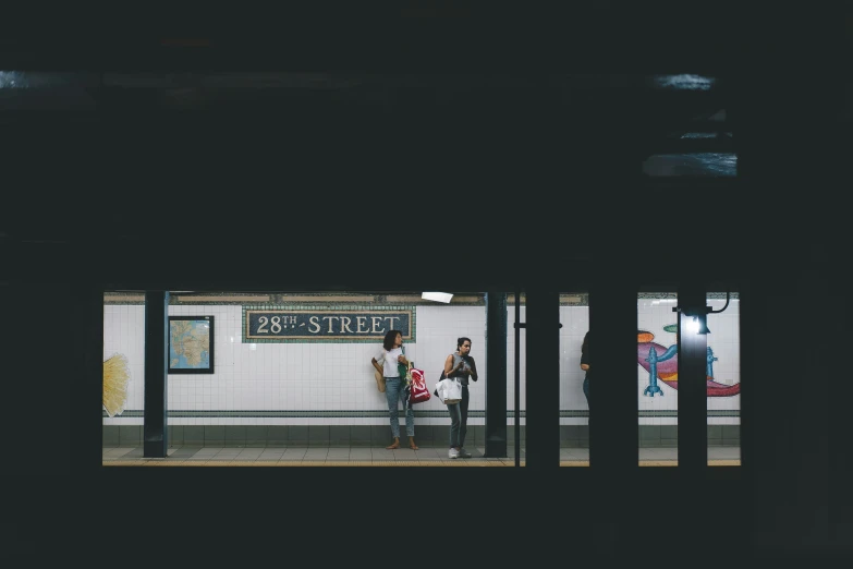 two people standing in front of a subway stop