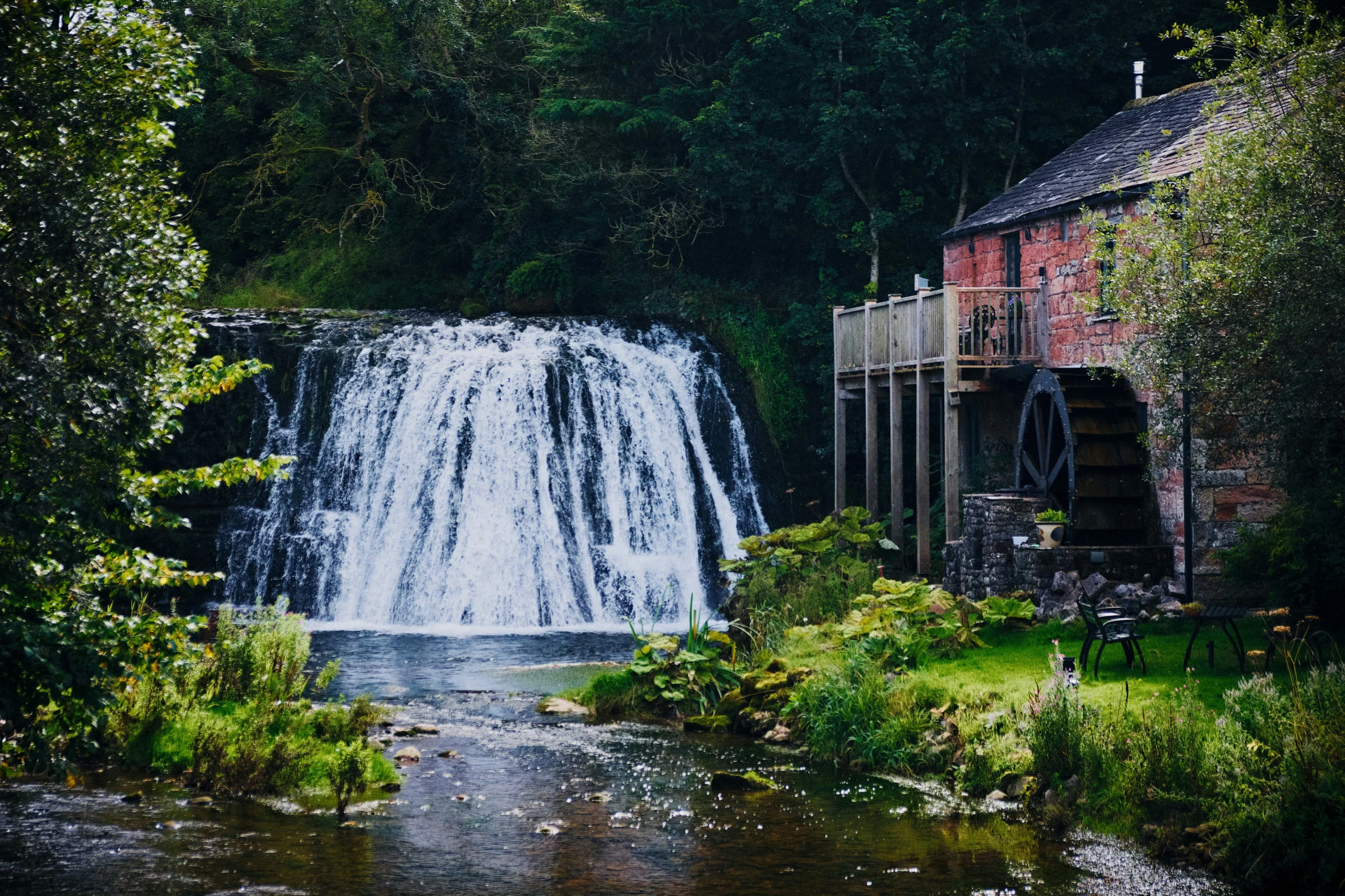 waterfall in a forest with a red building at the base