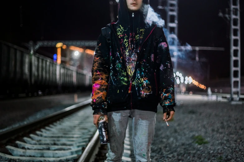 a young man is walking down a train track