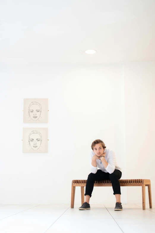 a man sitting on a bench next to two drawings