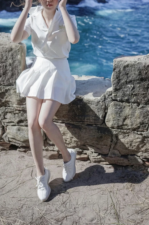 a woman is standing near water and wearing a hat