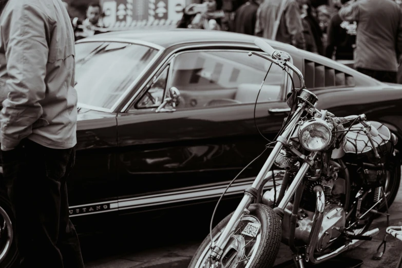 the person is standing next to a motorcycle in front of a car