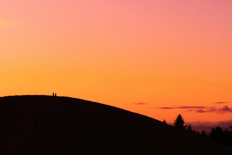 the silhouettes of people are on the hill top