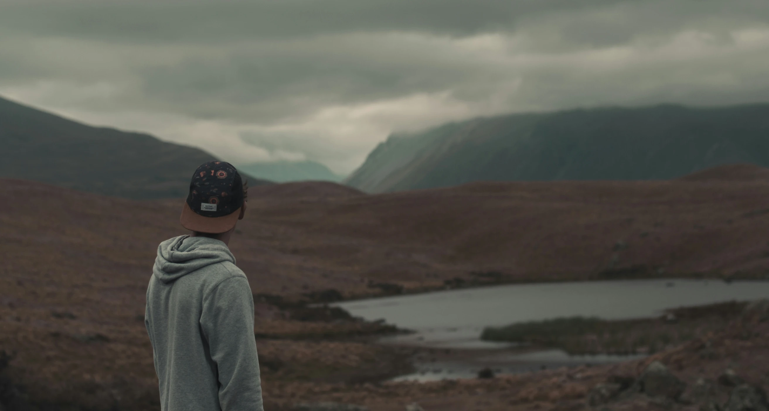 a man standing in a field looking at a lake